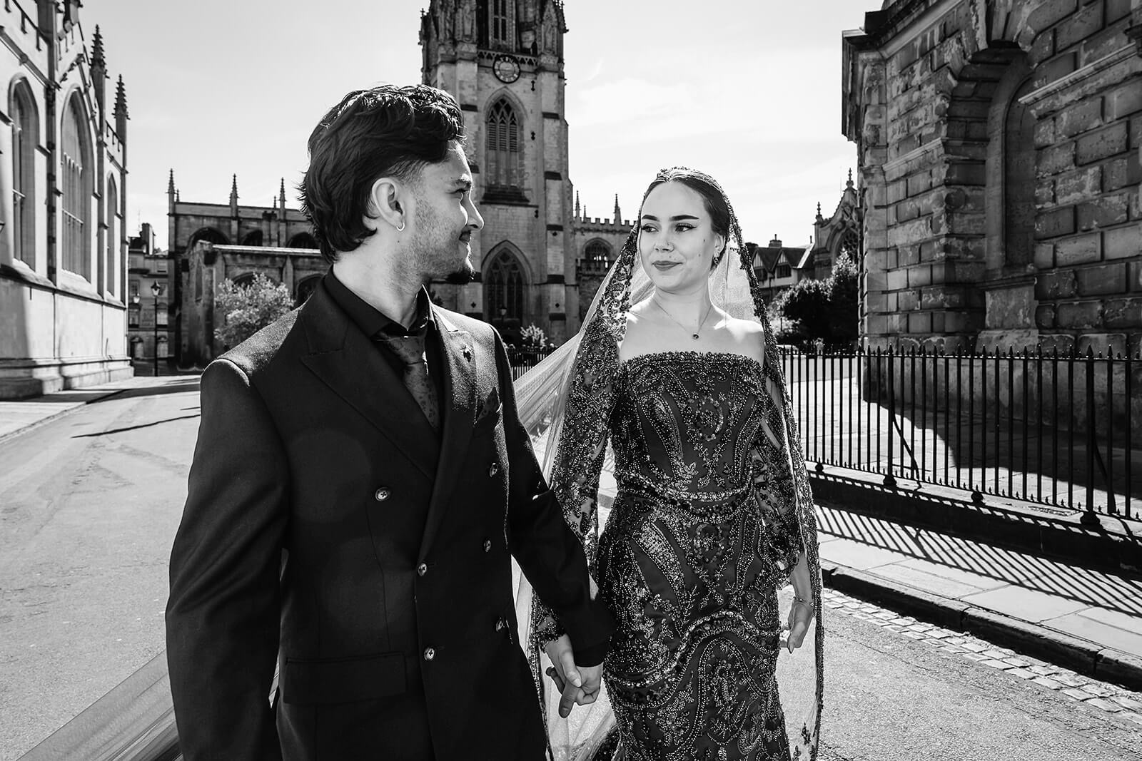 Couple walking, historic building backdrop | Oxford Nikkah wedding photos