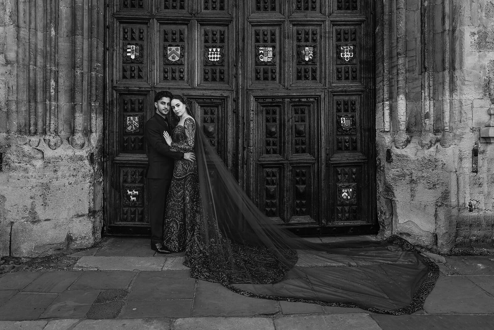 Bride and groom in elegant attire by ornate door in central Oxford | Nikkah wedding photography