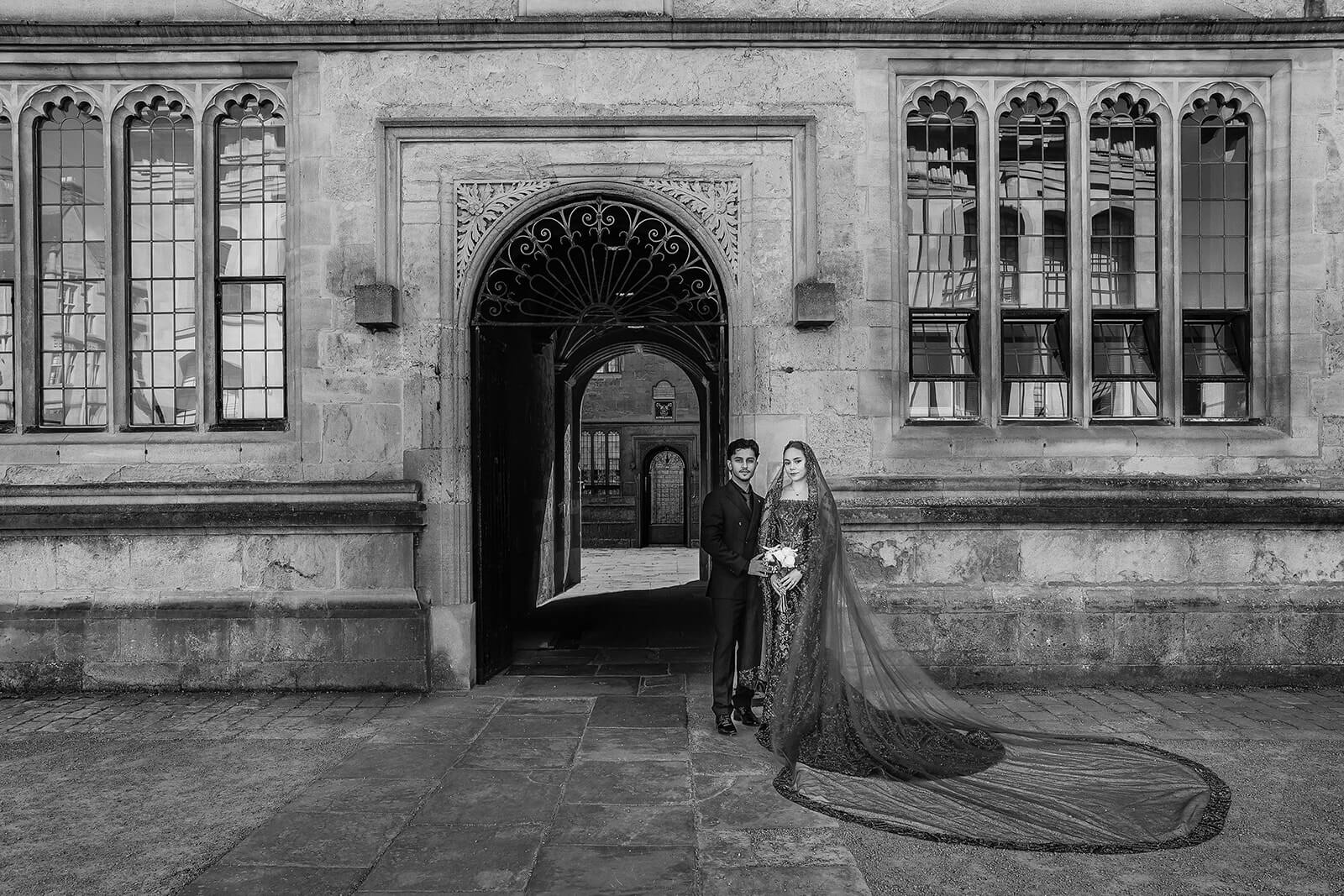 Couple in elegant attire by the Bodelain library building in central Oxford | Oxford Nikkah Wedding Photos.