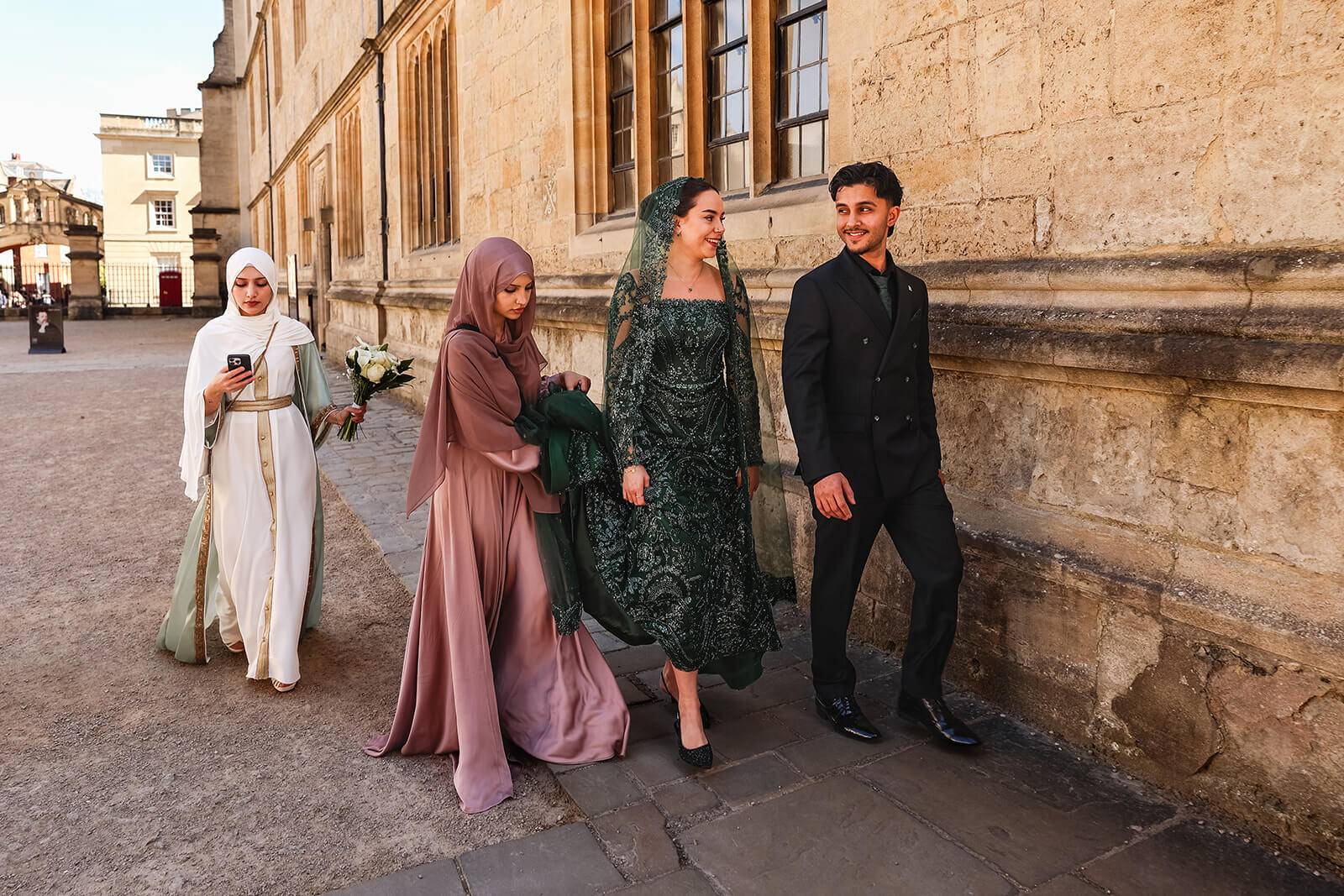 Four people walking in formal attire along the streets in central Oxford | Oxford Nikkah Wedding Photos